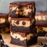 Close-up of stacked Cookie Dough Brownies with chocolate chips, topped with a shiny layer of chocolate ganache.