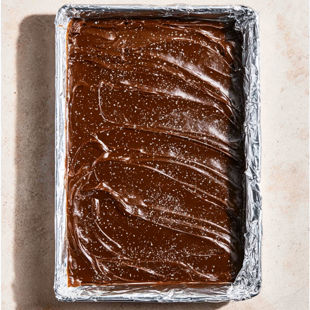 Easy Chocolate Matzo Crack Recipe 11 A tray of baked matzo covered with a smooth layer of dark chocolate, sprinkled with sea salt, and swirled for texture.