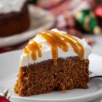 Slice of Gingerbread Cake with whipped cream and caramel drizzle.