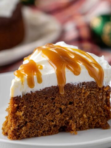 Slice of Gingerbread Cake with whipped cream and caramel drizzle.