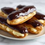 Homemade Eclairs Recipe filled with smooth pastry cream and topped with a glossy chocolate glaze.