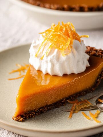 Easy Honey Carrot Pie Recipe 1 A slice of Honey Carrot Pie on a plate, topped with whipped cream and orange zest, showcasing the golden, smooth filling.