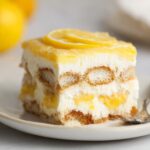 A slice of Lemon Tiramisu with layers of ladyfingers, creamy mascarpone, and lemon syrup, topped with lemon slices.