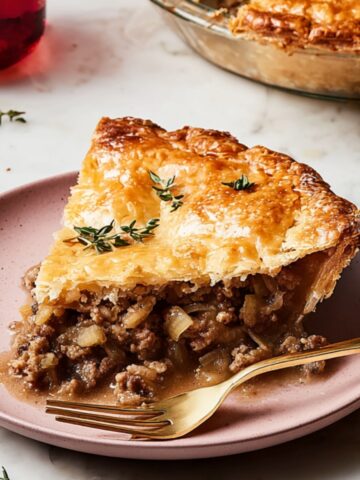 The Best Loaded Meat Pie Recipe 1 Slice of meat pie with flaky crust, garnished with thyme.