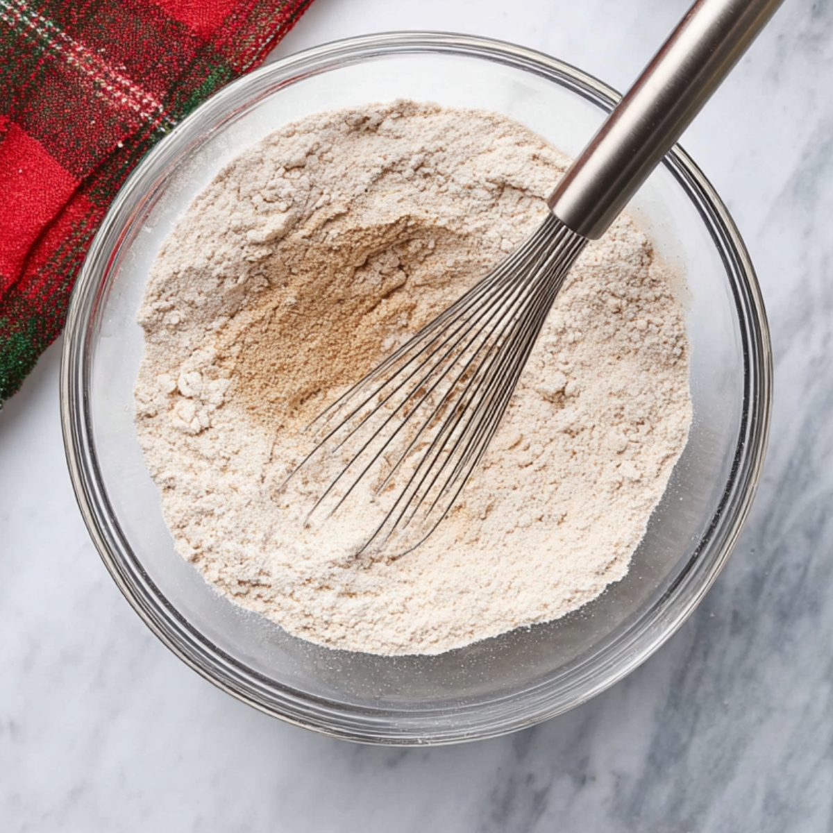 Dry ingredients for gingerbread cake in a bowl with a whisk.