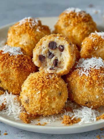 A plate of No Bake Moose Farts coated with graham cracker crumbs, with one ball cut open to reveal chocolate chips inside.