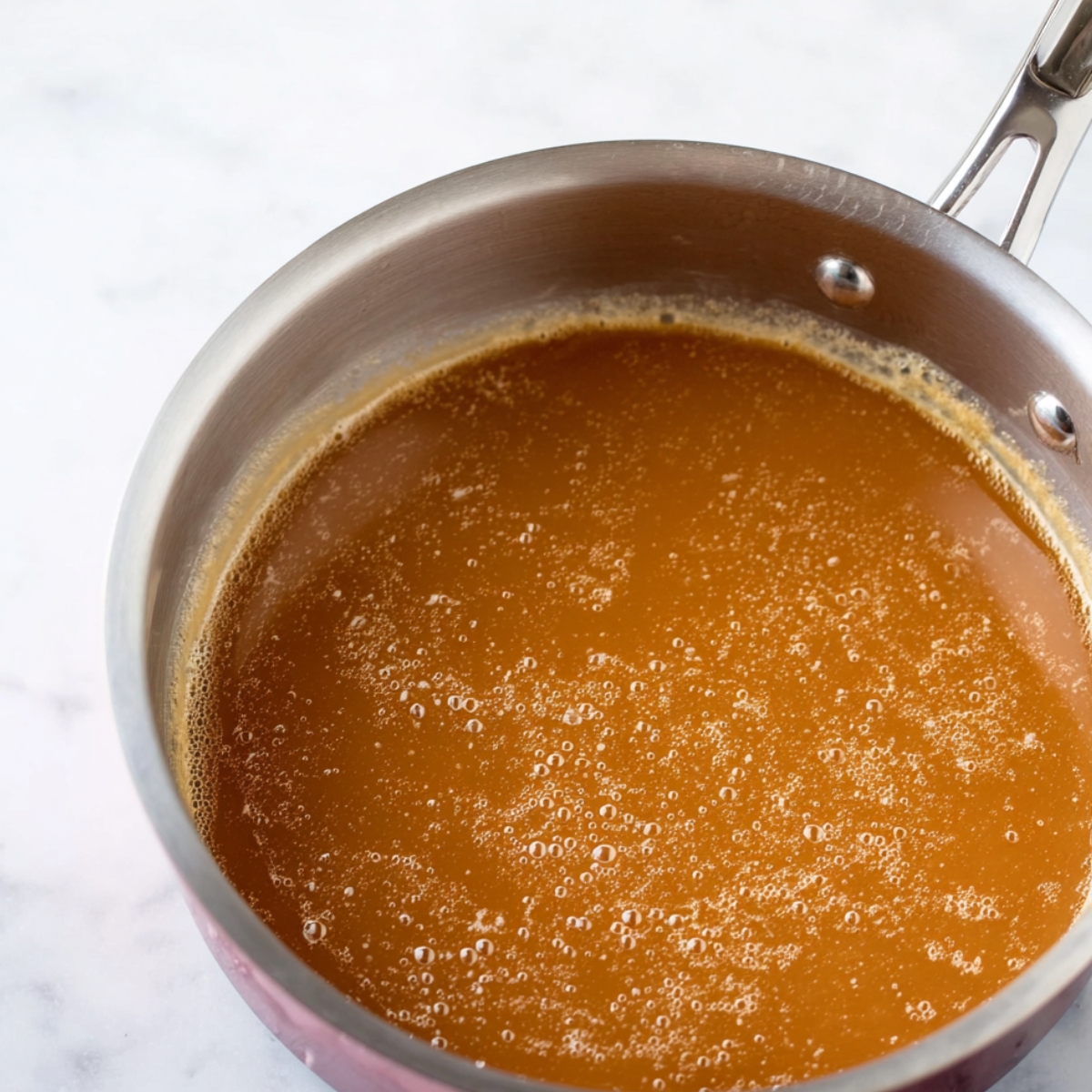 Best Knock You Naked Bars Recipe 11 Close-up of caramel layer cooking in a saucepan, with bubbles forming in the melted mixture.