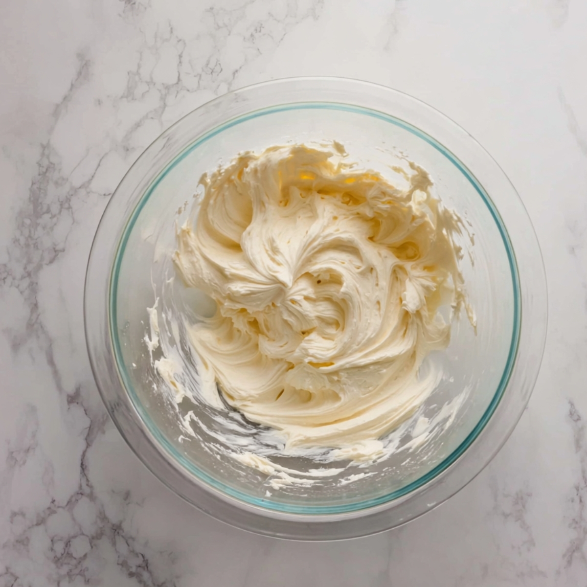 Easy Churro Cheesecake Cookies Recipe 10 A glass mixing bowl filled with smooth, creamy cream cheese filling, showing soft peaks and a well-mixed texture.