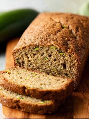 Moist Zucchini Bread Recipe 3 A freshly baked loaf of Zucchini Bread, sliced to reveal a soft, moist interior with visible zucchini pieces, set on a wooden board.