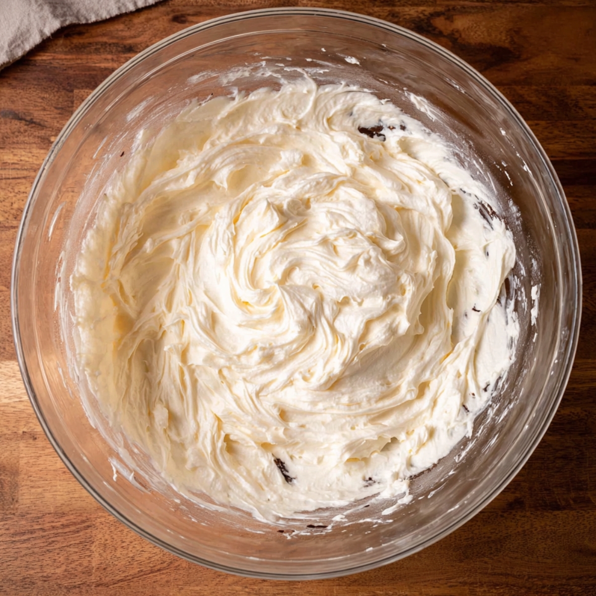 Best Chocolate Gooey Butter Cake Recipe 10 A glass bowl of creamy, whipped frosting, with a smooth, soft texture.