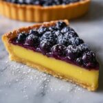 Slice of Blueberry Lemon Curd Tart with powdered sugar on top.