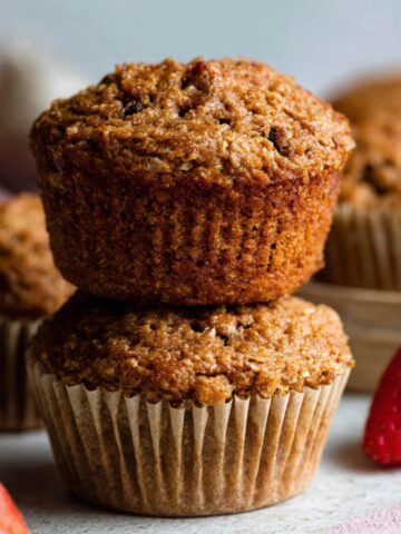 Healthy Bran Muffins Recipe 1 Freshly baked bran muffins, golden and crisp on top, stacked and ready to be enjoyed, with a side of strawberries.