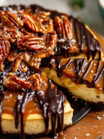 Best Caramel Turtle Cheesecake Recipe 1 A stunning Caramel Turtle Cheesecake topped with caramel sauce, chocolate drizzles, and candied pecans. A slice has been cut, showcasing the creamy interior and rich flavors.