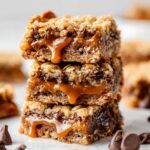 Three Carmelitas Recipe stacked on top of each other, with gooey caramel and chocolate chips oozing out between layers of crumbly oat crust.