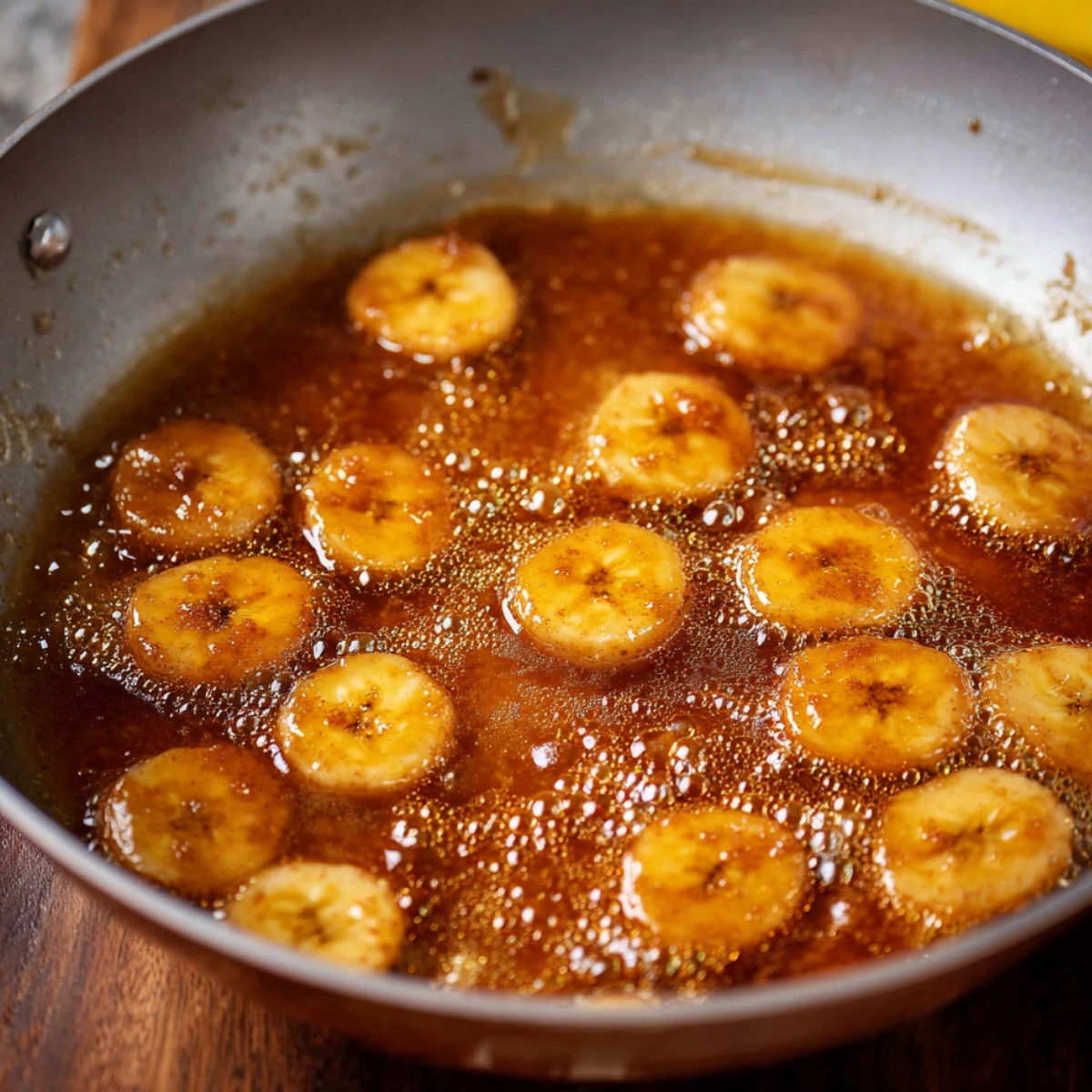 Easy Bananas Foster Cheesecake Recipe 11 Caramelized banana slices in a pan with syrup.