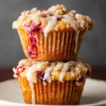Stack of baked Cranberry Orange Muffins with streusel and glaze.