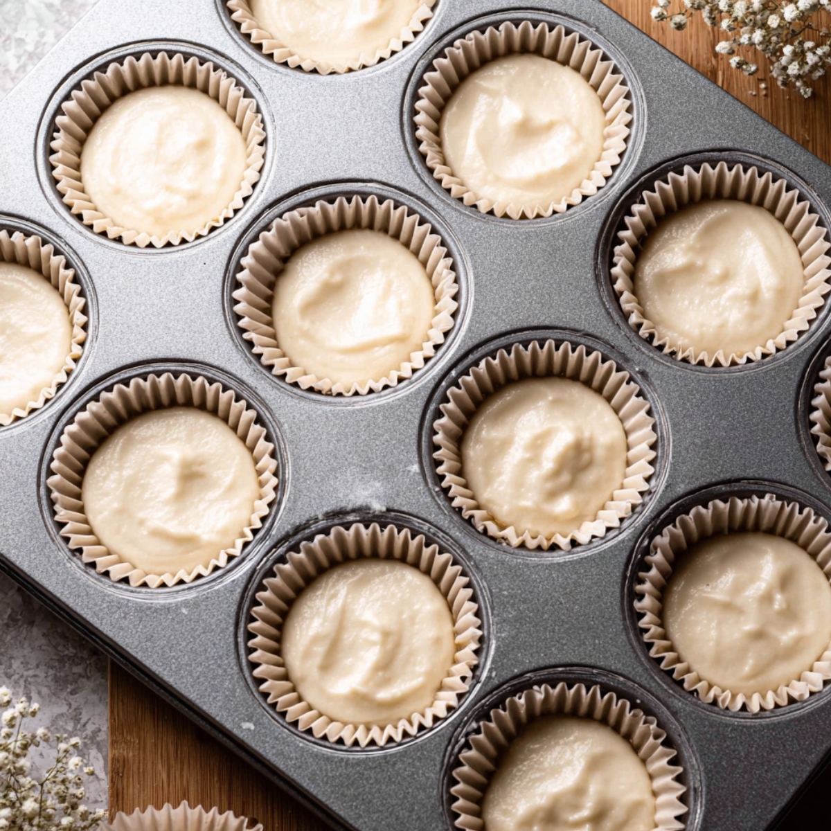 Homemade White Chocolate Cupcakes 10 Muffin tin filled with unbaked white chocolate cupcake batter, each in a paper liner, ready to be baked.