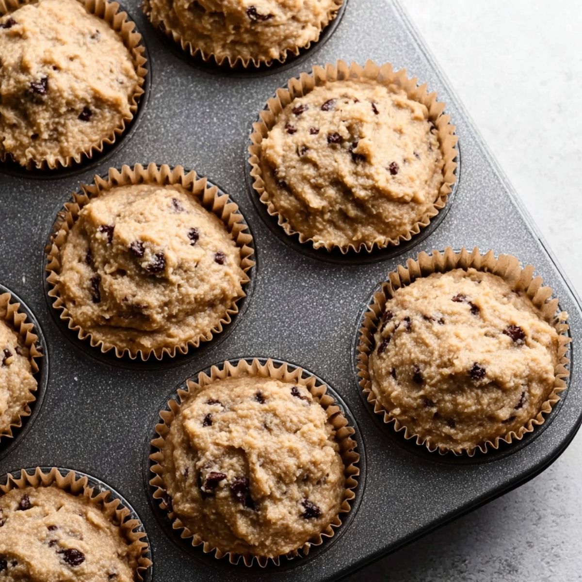 Healthy Bran Muffins Recipe 11 Unbaked muffin batter filled in paper-lined muffin cups, ready to be baked into delicious muffins.