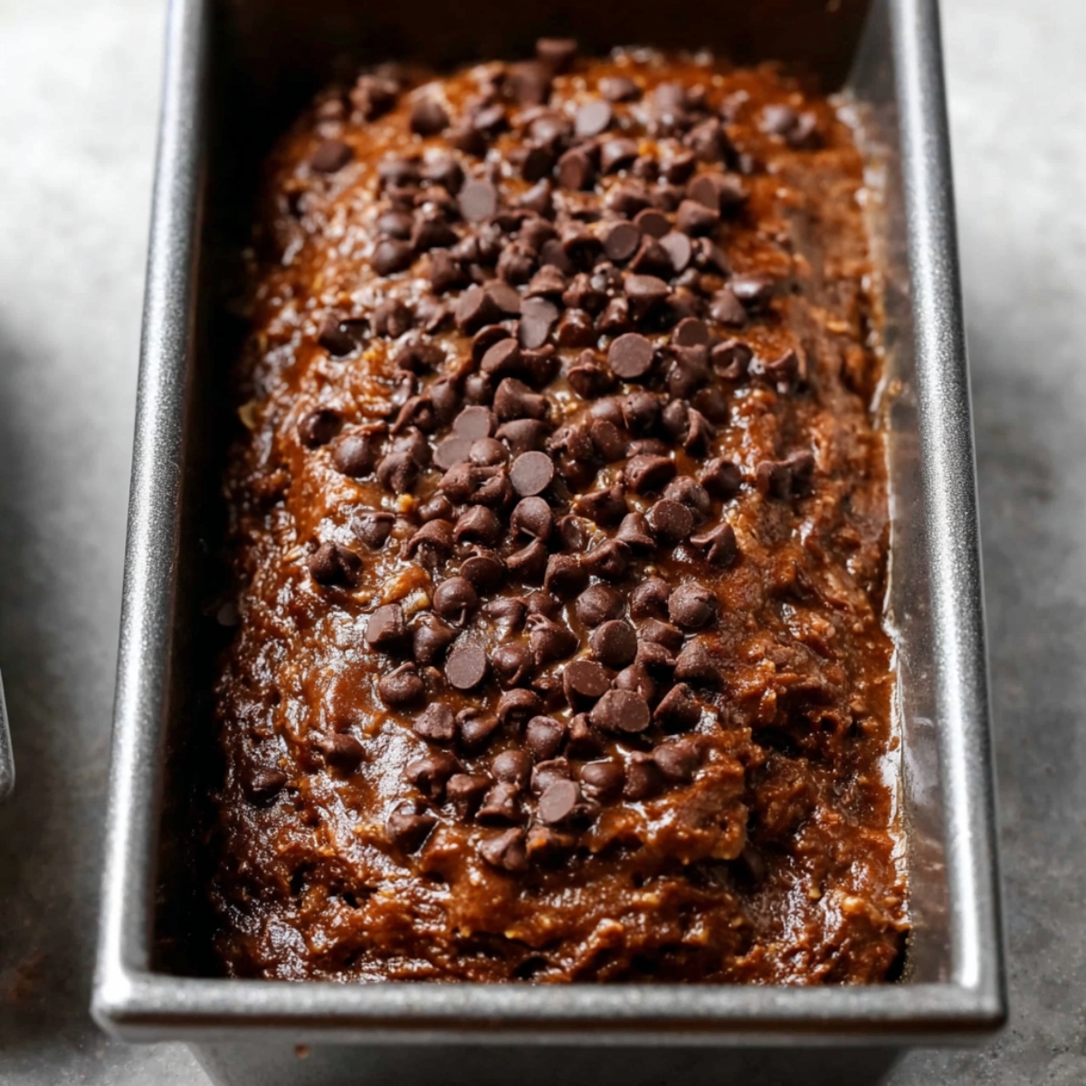 Double Chocolate Banana Bread 11 Chocolate banana bread batter in a loaf pan, topped with chocolate chips, ready to be baked.