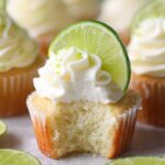 Close-up of a freshly baked Key Lime Cupcakes with a slice of lime and whipped cream.