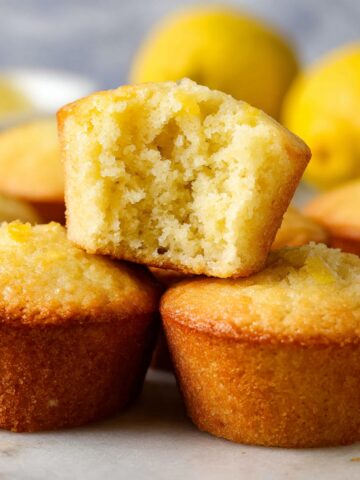 Healthy Lemon Muffins Recipe 4 Freshly baked lemon muffins, one of them is cut in half to reveal the soft, fluffy interior. The muffins are golden brown with a moist and airy texture, and the bright lemon flavor is evident.
