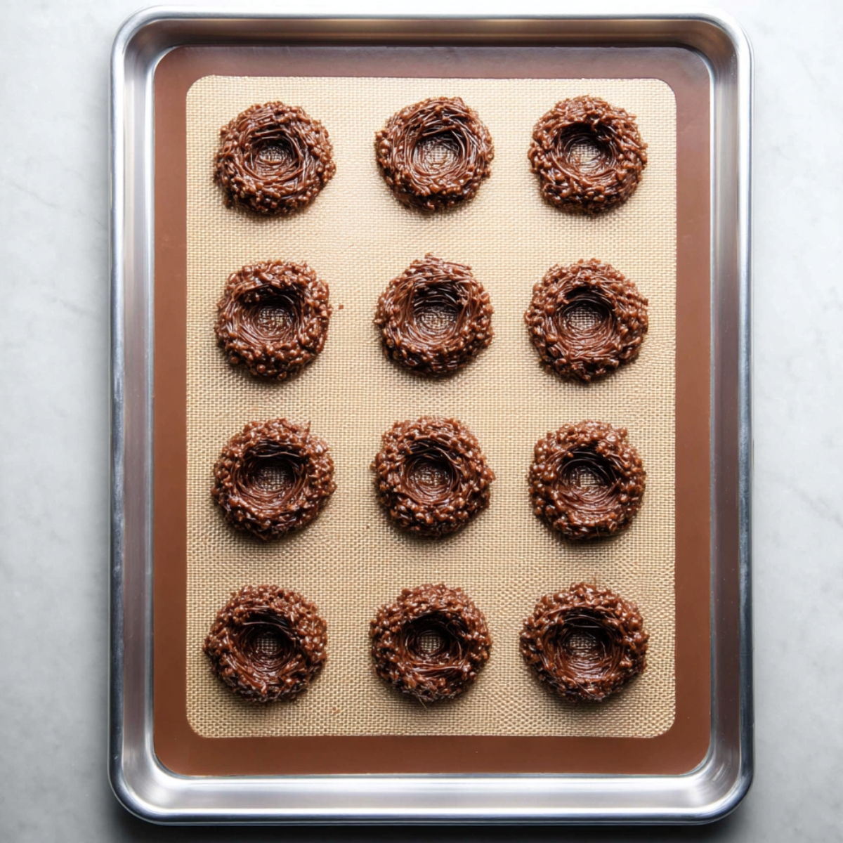 Quick Birds Nest Cookies Recipe 11 Twelve unbaked bird's nest cookies on a baking sheet, shaped with a center indentation.