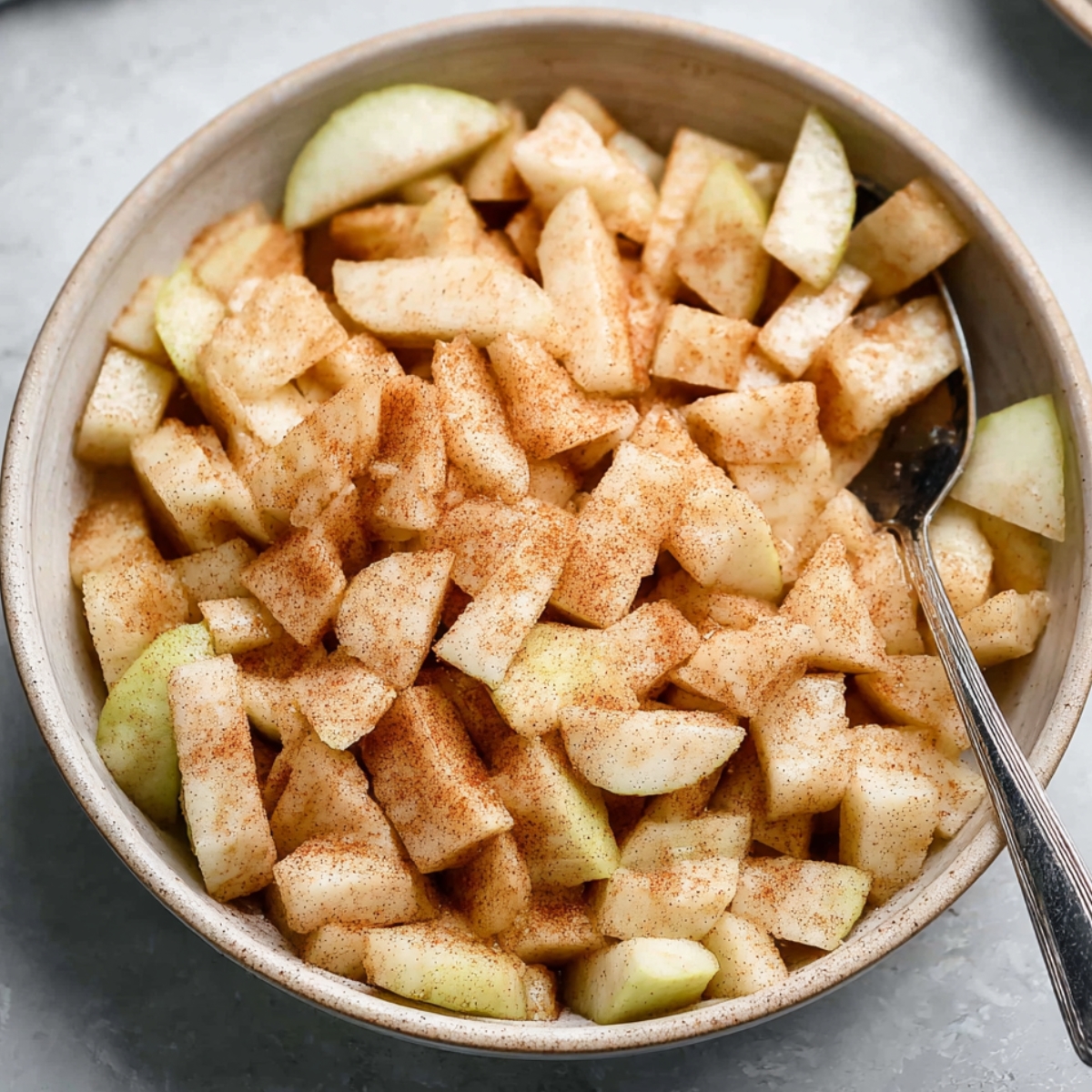 The Best Pear Crumble Recipe 10 Chopped pears coated with cinnamon and sugar in a mixing bowl, ready to be placed in a crumble dish.