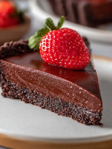 No Bake Chocolate Tart Recipe 3 A slice of No Bake Chocolate Tart with a smooth, creamy filling and a chocolate cookie crust, topped with a fresh strawberry.