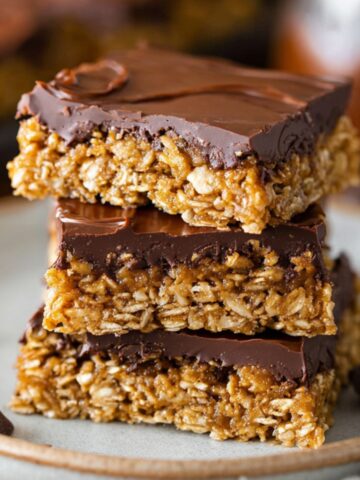 Healthy Nutty Chocolate Bars Recipe 1 A close-up of Nutty Chocolate Bars with a thick layer of chocolate on top, stacked on a plate, showcasing their delicious, chewy texture.