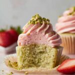 Pistachio Cupcakes topped with strawberry buttercream and pistachio bits.