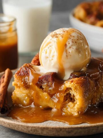 Easy Pumpkin Bread Pudding Recipe 2 A slice of pumpkin bread pudding topped with a scoop of vanilla ice cream, drizzled with caramel sauce, and garnished with a dusting of cinnamon.