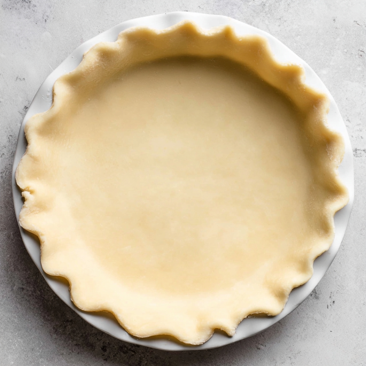Easy Mixed Berry Pie Recipe 11 A pie dish with an uncooked pie crust, crimped along the edges and ready to be filled with delicious filling for baking.