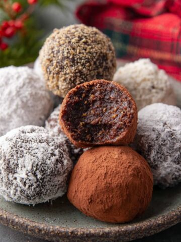 No-Bake Rum Balls Recipe 1 Plate of rum balls coated in sugar and cocoa, one cut in half.