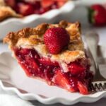 Slice of Strawberry Cardamom Rose Pie with a fresh strawberry on top.