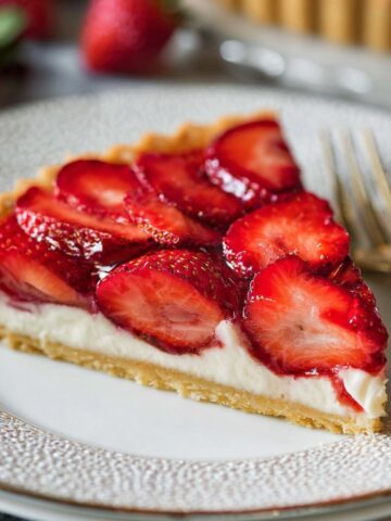 Homemade Strawberry Tart Recipe 1 A beautifully sliced strawberry tart with fresh, juicy strawberries arranged on top of a creamy filling and crisp tart crust. The slice reveals the creamy interior and golden crust.