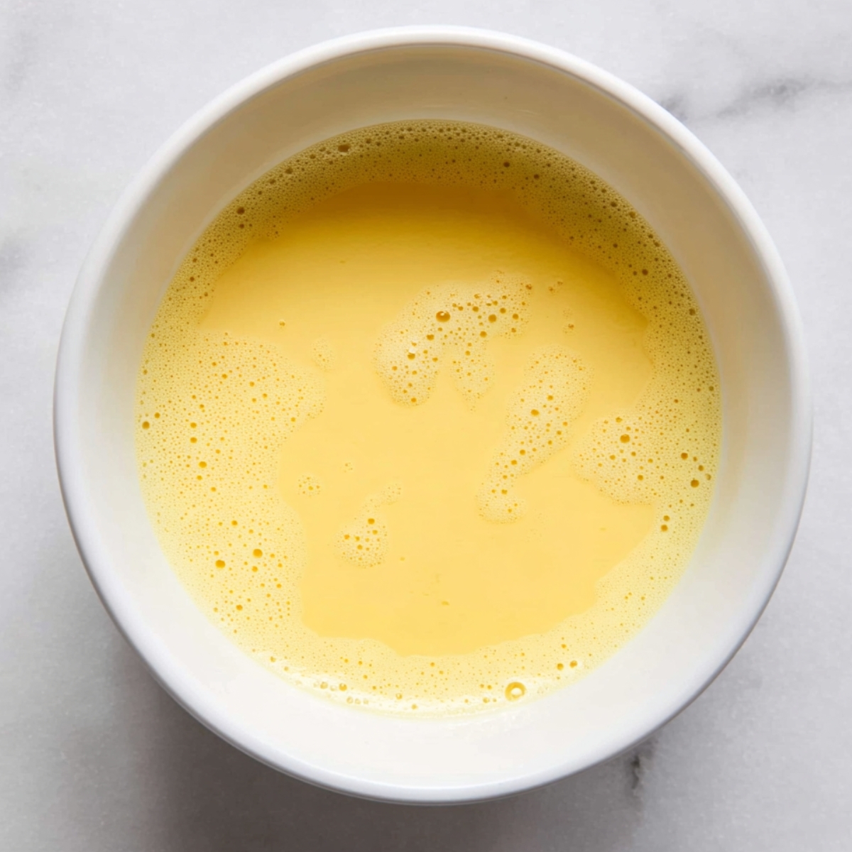 Easy Homemade Savory Galette Recipe 11 A bowl of freshly beaten eggs with a smooth, frothy yellow surface.