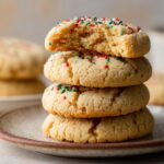 Stacked Almond Flour Sugar Cookies with festive red, green, and white sprinkles, top cookie partially bitten.