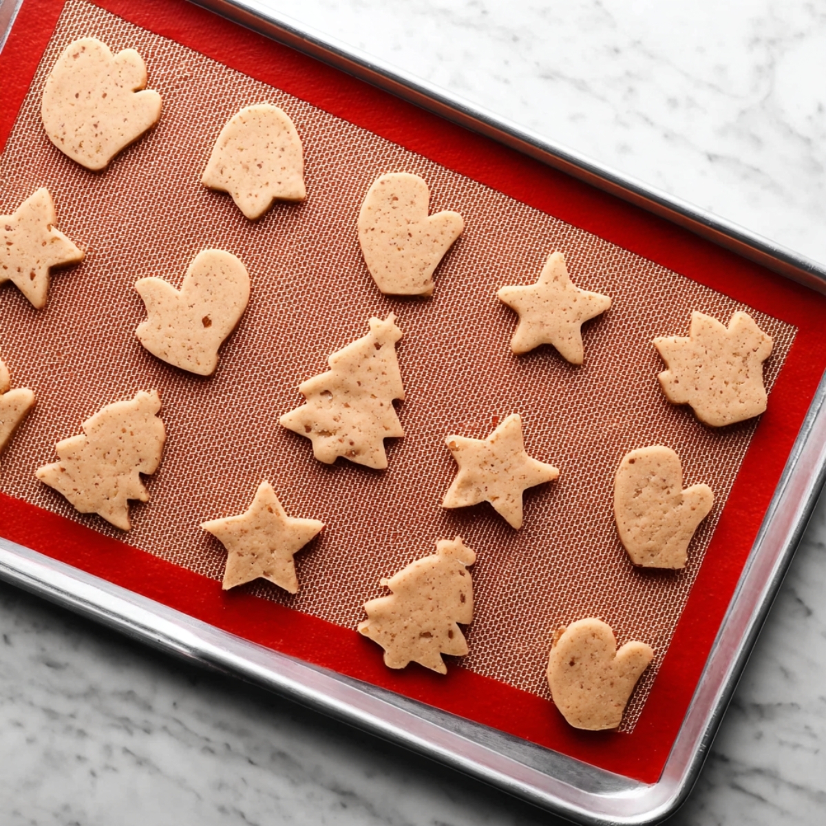 Pecan Sugar Cookies with Brown Butter Icing Recipe 11 Baked Christmas-shaped pecan sugar cookies on red silicone baking mat