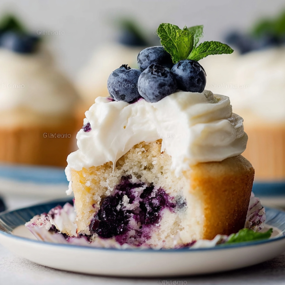 Bite-sized Blueberry Cream Cupcakes with frosting, blueberries, and mint.