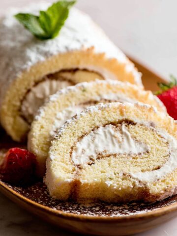 Easy Champagne Cake Roll Recipe 1 Slices of vanilla Swiss Champagne Cake Roll filled with whipped cream and dusted with powdered sugar, served with fresh strawberries and mint garnish.