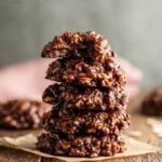 Stack of Chocolate Peanut Butter No-Bake Cookies on parchment paper, rich and glossy with oats.