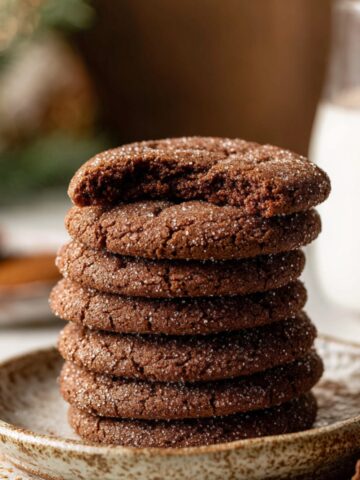 Easy Chocolate Snickerdoodles Recipe 1 Stack of freshly baked Chocolate Snickerdoodles cookies with sugar coating, one cookie partially bitten on top.