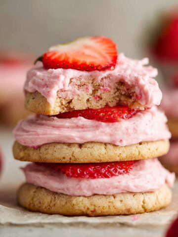 Frosted Strawberry Cookies Recipe 1 Three stacked Frosted Strawberry Cookies with pink frosting and fresh sliced strawberries on top, soft and chewy texture visible.