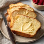Slices of soft Homemade Brioche bread served with butter on a plate.