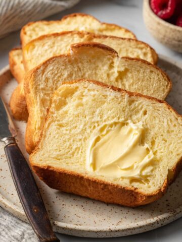 Easy Homemade Brioche Recipe 2 Slices of soft Homemade Brioche bread served with butter on a plate.