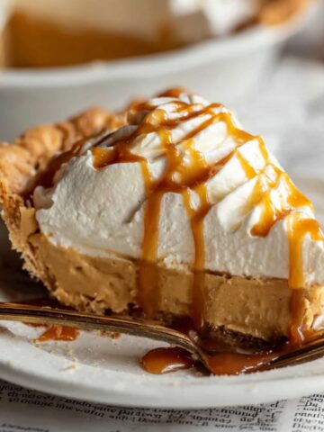 Easy Homemade Butterscotch Pie 2 Slice of homemade butterscotch pie topped with whipped cream and drizzled caramel sauce, served on a white plate with a fork.