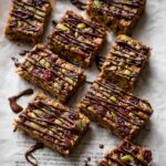 Salted Quinoa Granola Bars drizzled with chocolate on parchment paper.