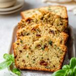 Slices of baked Savory Quick Bread with herbs and sun-dried tomatoes on a plate.