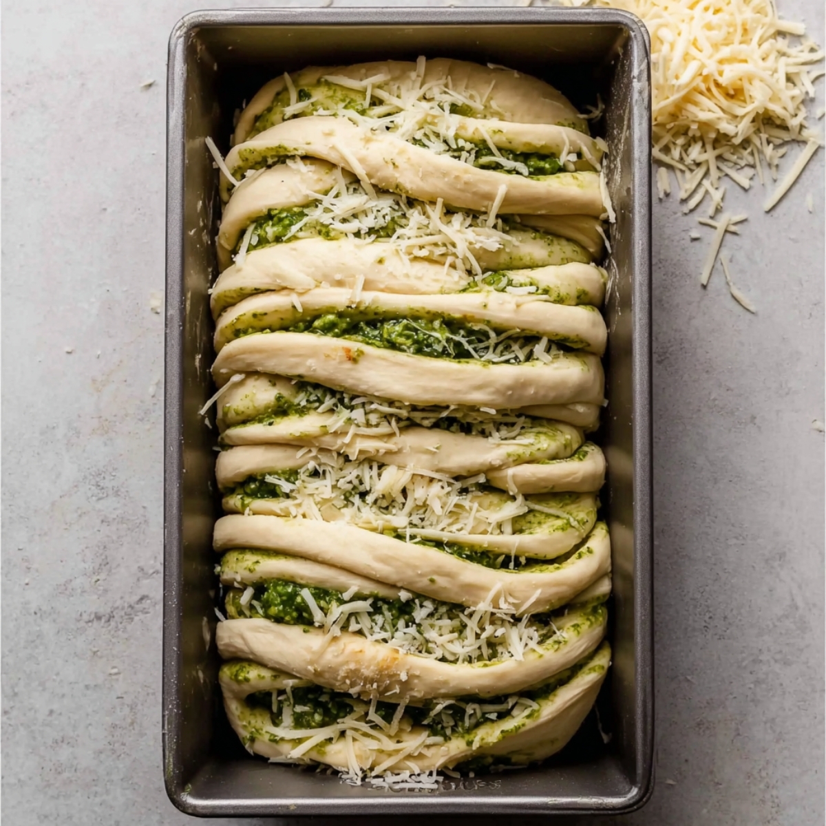 Homemade Pesto Pull Apart Bread 11 Pesto pull-apart bread in a pan, twisted dough filled with green pesto and cheese.