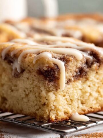 Cinnamon Roll Coffee Cake Recipe 1 Moist cinnamon roll coffee cake squares topped with vanilla glaze, showcasing swirls of cinnamon filling and a tender crumb.